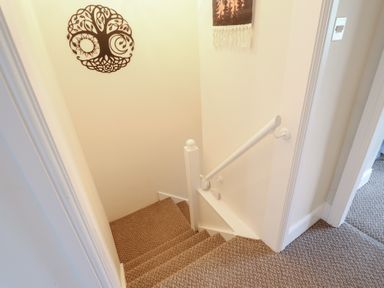 A staircase with a handrail and wall art at Golygfa in Pandy Tudur near Llanrwst