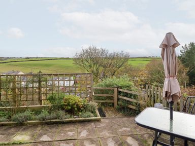 A garden with a table and umbrella overlooking fields at Golygfa Pandy Tudur near Llanrwst