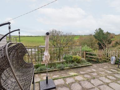 An outdoor area with a hanging chair and umbrella stand at Golygfa near Pandy Tudur