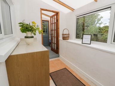 A hallway with a flower vase and wooden cabinet at Llain in Cardigan