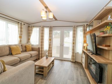 A living room with beige sofas a wooden coffee table TV and fireplace at 75 Foxburrow Hang in Fritton