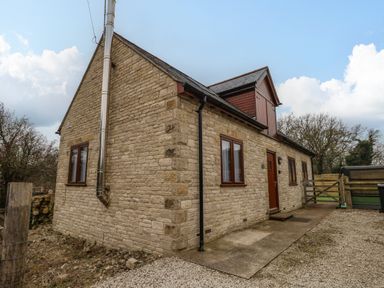 Exterior view of a stone house with multiple windows a door and a gravel driveway at Little Dairy House near Swanage