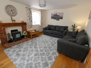 A living room with two dark sofas a fireplace a wooden coffee table and a gray rug at Little Dairy House near Swanage