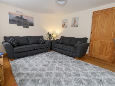 A room with two dark gray sofas a gray rug a wooden door and wall art at Little Dairy House near Swanage