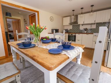 A dining table set with blue dishes and a vase of tulips in a kitchen at Little Dairy House near Swanage
