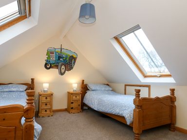 A bedroom with two wooden single beds two bedside tables and skylight windows at Little Dairy House near Swanage