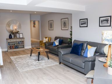 A living room with two sofas a wooden coffee table a bookshelf a round mirror and framed pictures on the walls at Daly's Place in Ballyporeen County Tipperary