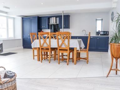 A kitchen with blue cabinets and a wooden dining table with six chairs at Daly's Place in Ballyporeen County Tipperary
