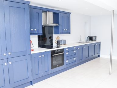 A kitchen with blue cabinets white countertops an oven a stove a toaster a microwave and a sink at Dalys Place Ballyporeen County Tipperary