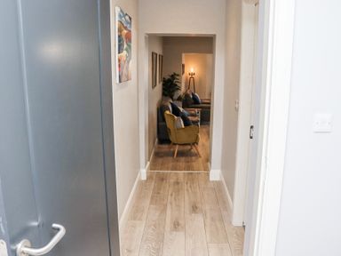 A hallway with light wood flooring leading to a living area with chairs a sofa and framed pictures on the wall at Daly's Place Ballyporeen County Tipperary