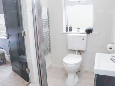 A bathroom with a toilet sink window with toiletries and towel at Daly's Place in Ballyporeen County Tipperary