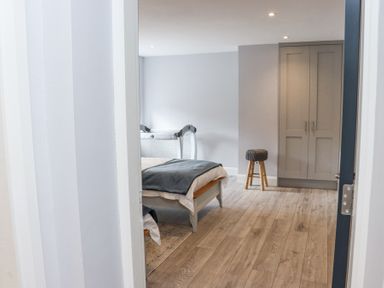 A bedroom with a bed a small stool a wardrobe and a baby crib at Daly's Place in Ballyporeen County Tipperary