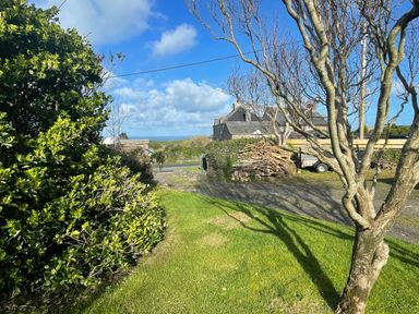 A garden with bushes and a view of a house at Puffin Cottage in Tintagel