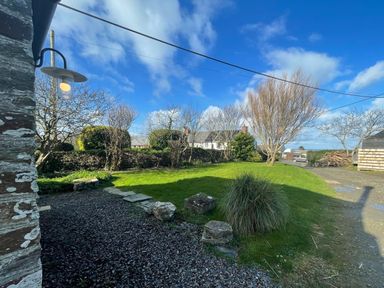 A garden with grass and trees at Puffin Cottage in Tintagel