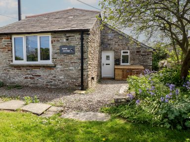 A house with a sign and flowerbed at Puffin Cottage in Tintagel