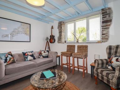 A living room with a map on the wall and a guitar at Puffin Cottage in Tintagel