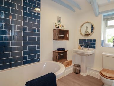 A bathroom with a bath tub and sink at Puffin Cottage in Tintagel