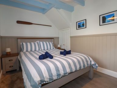 A bedroom with a striped bed and bedside tables at Puffin Cottage in Tintagel