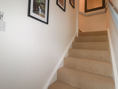 A staircase with framed pictures on the wall at Puffin Cottage in Tintagel