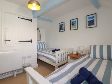 A bedroom with two beds and a bedside table at Puffin Cottage in Tintagel