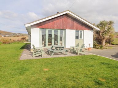 A patio with outdoor chairs and a picnic table in front of a house named Seafield in Rhydwyn near Cemaes Bay