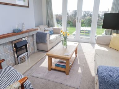 A living room with two sofas a wooden coffee table with flowers and a fireplace at Seafield in Rhydwyn near Cemaes Bay