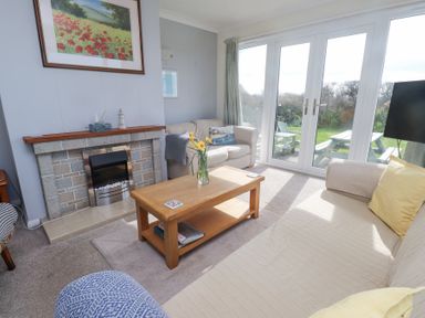 A living room with sofas a wooden coffee table a fireplace and glass doors opening to a garden at Seafield in Rhydwyn near Cemaes Bay