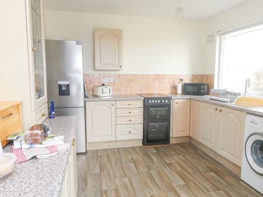 A kitchen with a refrigerator oven toaster microwave and washing machine at Seafield in Rhydwyn near Cemaes Bay
