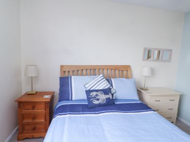 A bedroom with a bed with blue and white bedding flanked by two bedside tables with lamps at Seafield in Rhydwyn near Cemaes Bay