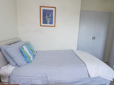 A bedroom with a bed with striped bedding pillows and a framed flower picture on the wall at Seafield in Rhydwyn near Cemaes Bay