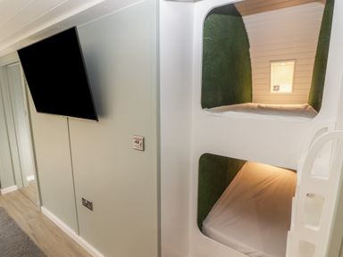 A room with bunk beds built into the wall and a wall mounted television at The Hazel Pod in Cowbridge