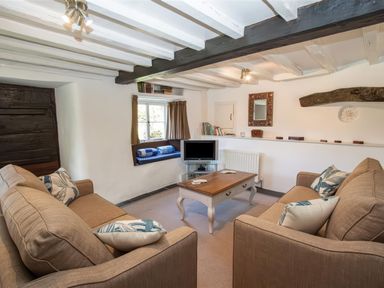 A living room with two sofas a coffee table a small television and a window seat at The Cragg in Hawkshead