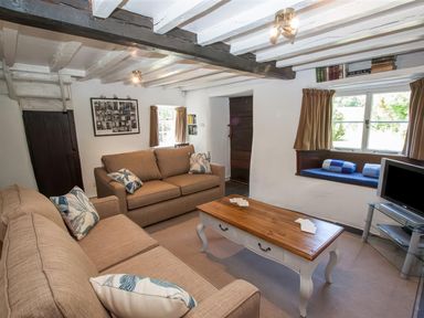 A living room with two sofas a wooden coffee table a TV on a stand and a window seat at The Cragg in Hawkshead