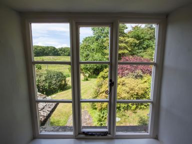 A view of a garden and trees through a window at The Cragg in Hawkshead