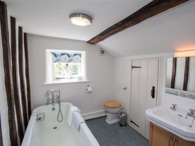 A bathroom with a bathtub toilet and sink with mirror at The Cragg in Hawkshead