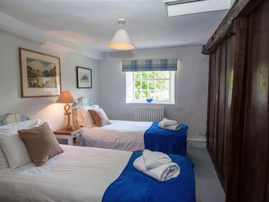 A bedroom with two single beds a lamp on a bedside table and a window at The Cragg in Hawkshead