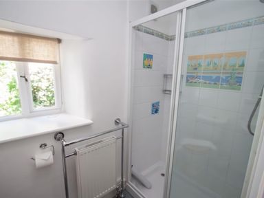 A bathroom with a shower enclosure a radiator and a window with a blind at The Cragg in Hawkshead
