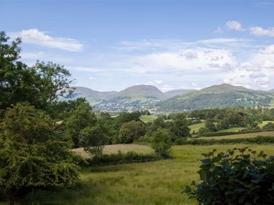 A countryside landscape with trees hills and a blue sky at The Cragg in Hawkshead
