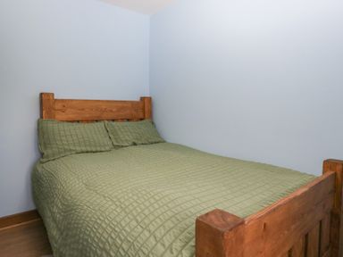 A bedroom with a wooden bed and green bedding at Howgill Head in Kendal