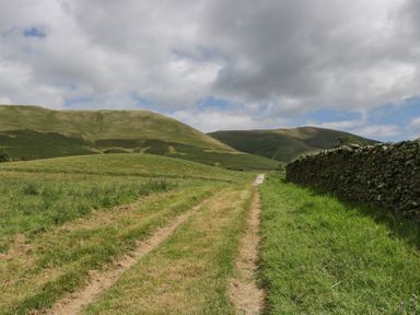 A road alongside a stone wall and hills at Howgill Head in Kendal