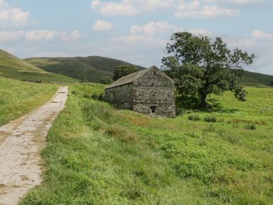 A stone building near a pathway surrounded by grass at Howgill Head in Kendal