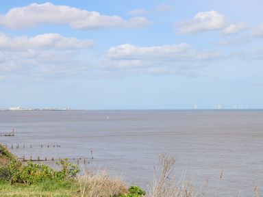 A coastal view with the sea in the foreground and wind turbines on the horizon at 98 Waterside Park in Corton