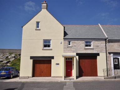 A street view of a house with two wooden garage doors and a red entrance door at Sunset Lodge in Fortuneswell
