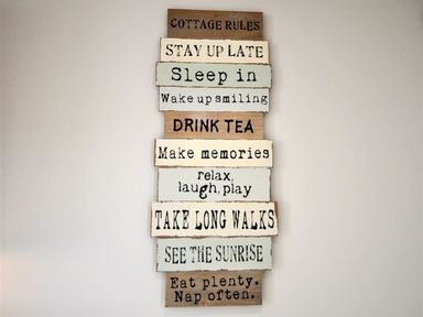 A wall decoration with wooden signs displaying cottage rules at Sunset Lodge in Fortuneswell