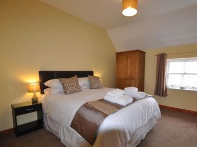 A bedroom with a double bed bedside table and lamp wardrobe and window at Sunset Lodge in Fortuneswell