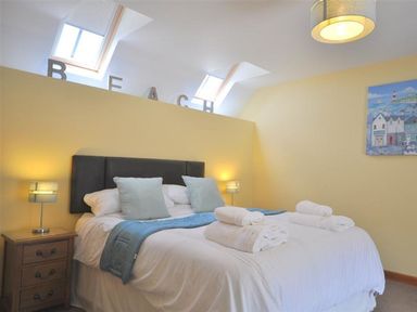 A bedroom with a double bed with folded towels bedside tables lamps and skylights at Sunset Lodge in Fortuneswell