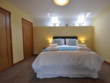 A bedroom with a bed with pillows and folded towels and wooden doors at Sunset Lodge in Fortuneswell