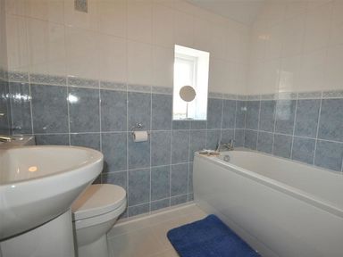 A bathroom with a sink toilet bathtub blue tiles and a blue bath mat at Sunset Lodge in Fortuneswell