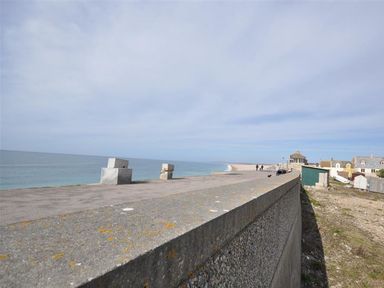A concrete sea wall along a beach with houses and a path at Sunset Lodge in Fortuneswell