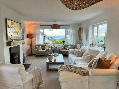 A living room with sofas armchairs a coffee table and a fireplace at Trem Ynys 3 bed in Abersoch